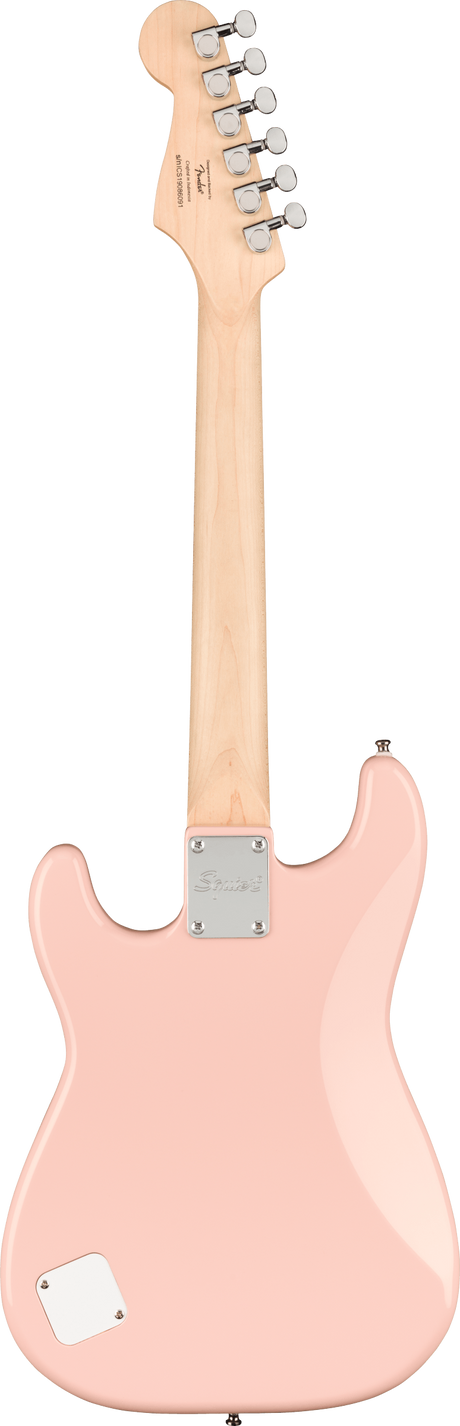 The image shows the back of a pink/coral Squier electric guitar with a maple neck and six chrome tuning pegs on the headstock. It features a contoured Stratocaster-style body, a chrome neck plate for the bolt-on neck, and a battery or control cavity cover on the lower bout. The finish is solid, highlighting the classic design typical of Squier, Fender’s affordable brand.