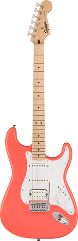 The image shows a Squier Stratocaster-style electric guitar with a coral pink contoured body and white pickguard. It features three pickups—two single-coils and a humbucker at the bridge—chrome hardware, a maple neck and fretboard with black dot inlays, and six-in-line chrome tuners. The Squier logo is visible on the headstock. This guitar offers a classic Fender look at an affordable price.