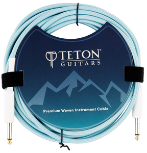 The image shows a Teton Teal 20ft guitar cable from the front, highlighting its teal-colored, coiled cable with metal connectors on both ends. The connectors have a durable, sleek design, and the cable appears flexible yet sturdy, suitable for professional guitar use. The background is plain, emphasizing the cable’s features and vibrant color.