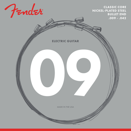 The image shows a package of Fender electric guitar strings with the red Fender logo. The strings are coiled in a circle, labeled as light gauge .009-.042. It specifies Classic Core Nickel-Plated Steel with Bullet End and has a "Made in the USA" mark. These strings are designed for Fender tremolo systems, offering balanced tone and good magnetic response.