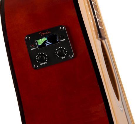 The image shows a close-up of a Fender preamp/pickup system installed in a red/burgundy acoustic-electric guitar. The black control panel features a digital LCD tuner with green lights, the Fender logo, two knobs labeled "VOLUME" and "TONE," a "TUNER" button, and a battery indicator. This electronics system enables amplification and tuning while preserving the guitar's acoustic tone for live or recording use.