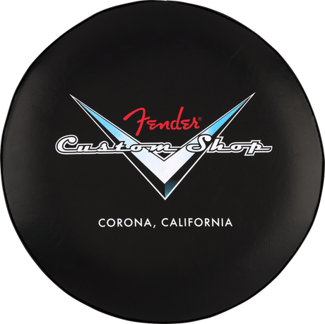 The image shows a circular black stool top featuring the Fender Custom Shop logo. The logo includes the red Fender script above white "Custom Shop" text within a V-shaped design with blue and white accents. Below, it reads "CORONA, CALIFORNIA," referencing Fender’s Custom Shop location. This branded seat likely suits music stores, guitar shops, or studios, appealing to Fender fans and guitar enthusiasts.
