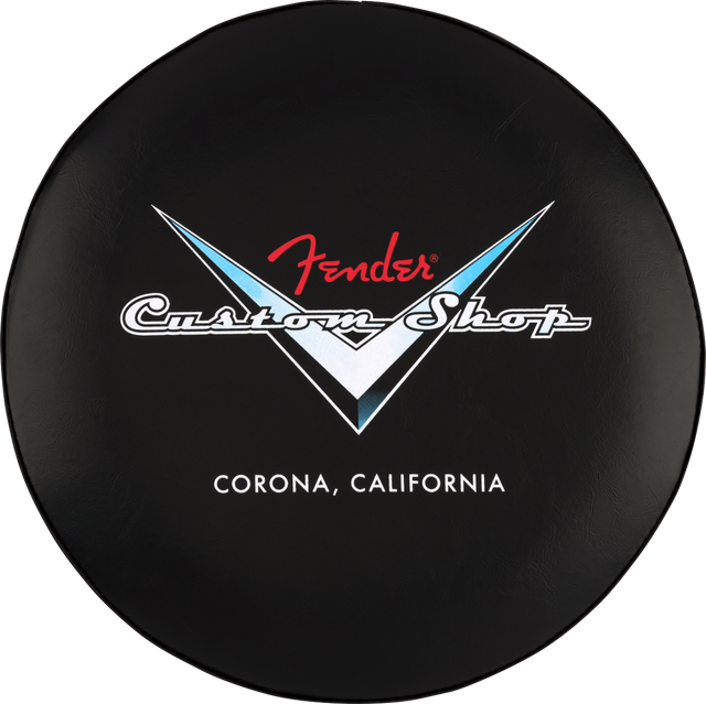 The image shows a circular black stool top featuring the Fender Custom Shop logo. The logo includes the red Fender script above white "Custom Shop" text within a V-shaped design with blue and white accents. Below, it reads "CORONA, CALIFORNIA," referencing Fender’s Custom Shop location. This branded seat likely suits music stores, guitar shops, or studios, appealing to Fender fans and guitar enthusiasts.