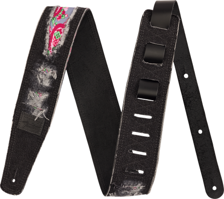 The image shows a black guitar strap featuring colorful floral and paisley patterns in pink and green along its center, with gray feather-like designs and a black leather patch. It has adjustable holes, reinforced ends for attachment, and padding for shoulder comfort. Combining functionality with decorative art, this strap suits various musical styles and helps guitarists play while standing.
