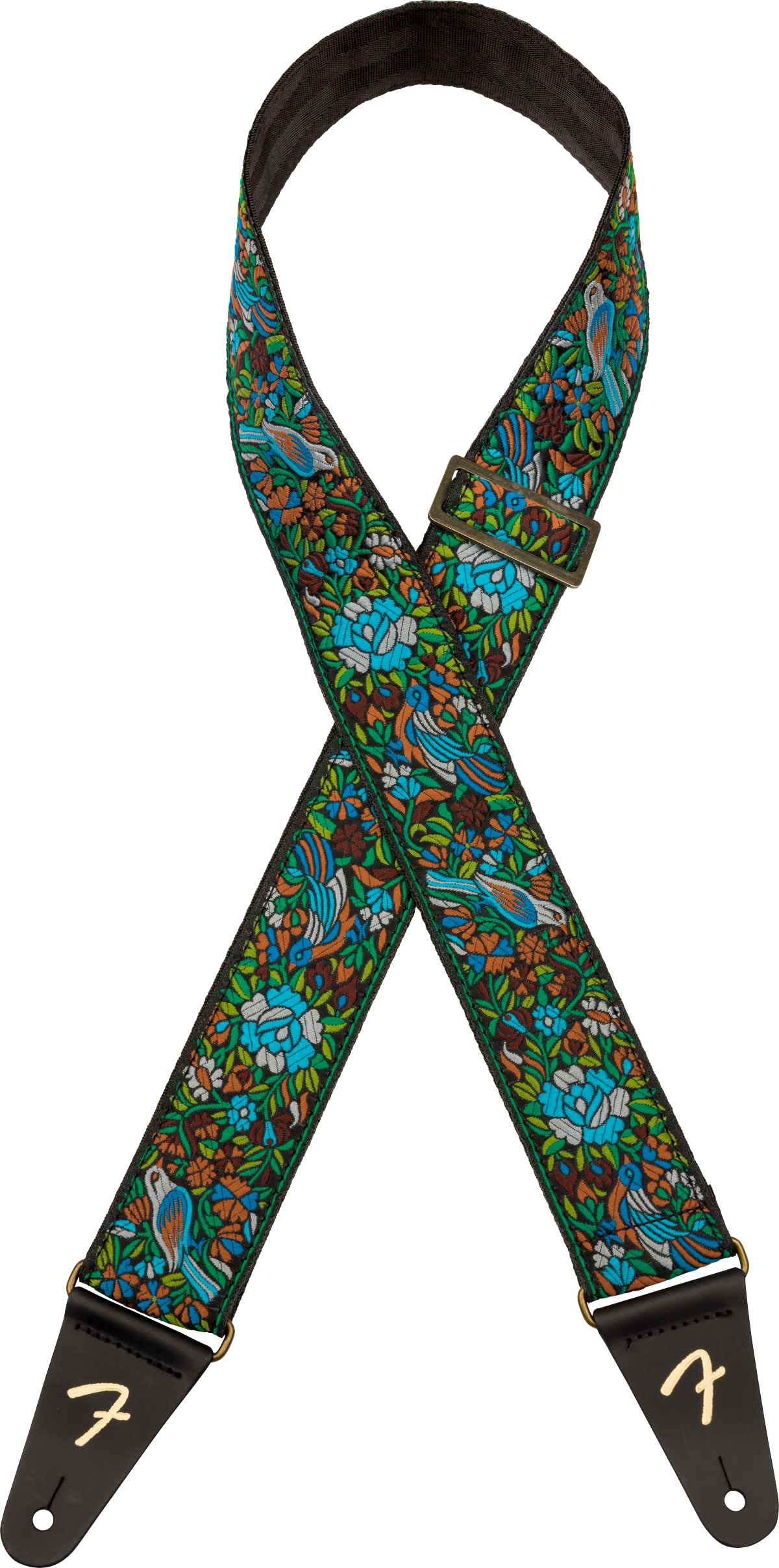 The image shows a vibrant Fender guitar strap with a detailed tropical pattern featuring birds, foliage, and bright colors like blues, greens, and browns. It has black leather ends embossed with the Fender "F" logo, metal hardware, and an adjustable buckle. The neck area includes black padding for comfort, combining both decorative style and functional support for playing guitar while standing.