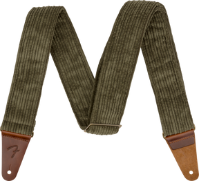 The image shows a guitar strap made of olive green corduroy fabric with ribbed texture and brown leather end tabs. It features an adjustable slider mechanism and a "Fender" logo embossed on one leather end. Designed for comfort and durability, the strap securely attaches to guitars, making it suitable for both acoustic and electric instruments.