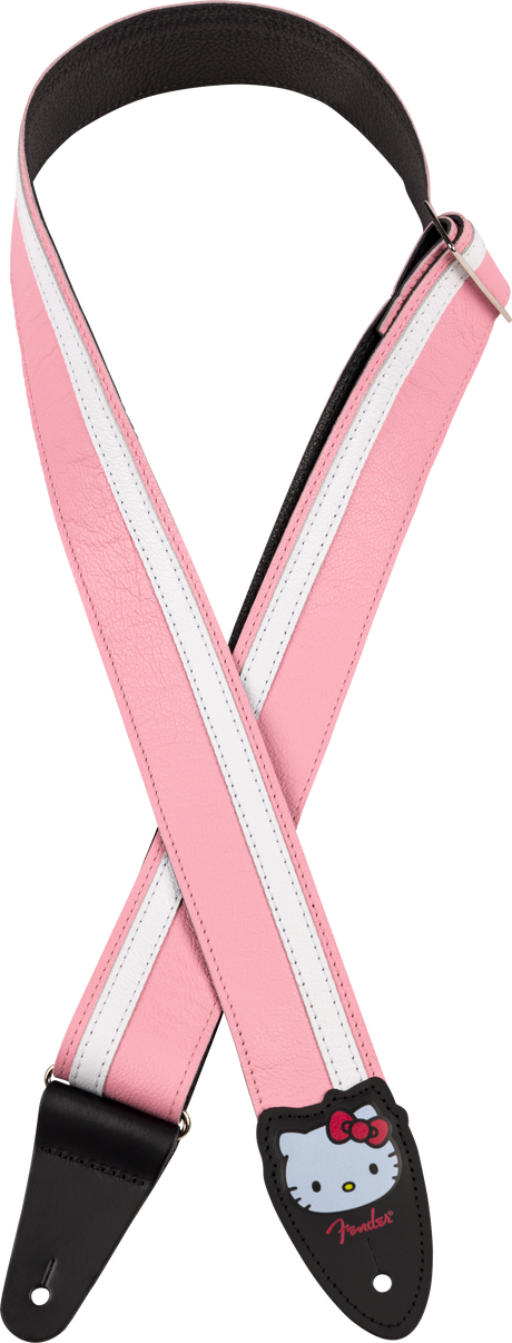 The image shows a pink and white striped guitar strap with black leather ends. One end features a Hello Kitty design and the red Fender logo. This themed strap adds personality for Hello Kitty fans and guitarists, providing support by distributing the instrument's weight. The leather ends securely attach to the guitar's strap buttons or locks.