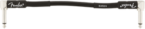 The image shows a black Fender guitar strap with the iconic Fender logo on the left side and additional branding on the right. It features white or silver metal hardware at both ends for attaching to a guitar’s strap buttons. This accessory helps musicians comfortably wear their guitar while standing by distributing the instrument’s weight across the shoulder and body.