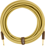 The image shows a Fender guitar cable with a woven tweed yellow-brown fabric jacket, gold-plated 1/4" TS connectors, and brown leather-style cable ties featuring the Fender logo. Designed for electric guitars and instruments, it connects to amps and pedals. The vintage-style woven exterior provides durability and matches Fender’s classic look while ensuring good signal clarity.