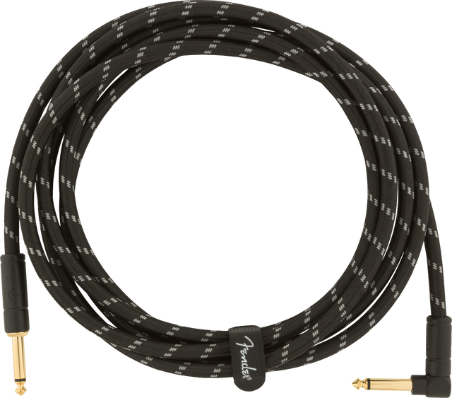 The image shows a coiled musical instrument cable with a black braided exterior featuring a white zigzag pattern. It has gold-plated 1/4" TS connectors—one straight and one right-angle. A cable tie with the "Fender" logo secures it. Designed for electric guitars, basses, and other instruments, the durable braided jacket and gold connectors ensure reliable performance and corrosion resistance.