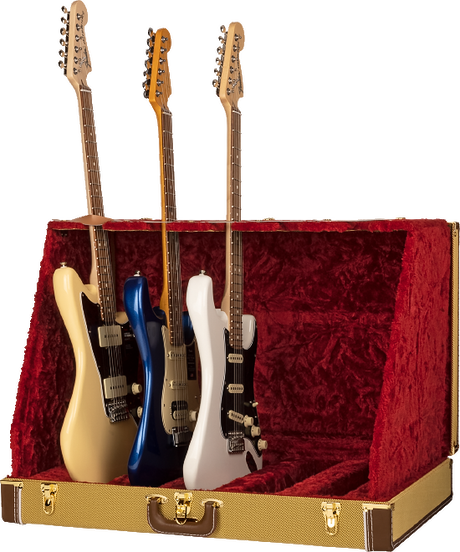 The image shows a vintage-style tweed guitar case or display stand with a red velvet interior holding three Stratocaster-style electric guitars. From left to right, the guitars are cream, blue, and white, each featuring single-coil pickups, tremolo bridges, maple necks with rosewood fretboards, and six strings. The case appears designed for elegant presentation or collector display.
