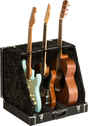 The image shows a professional black hard case/display stand with plush lining designed to hold and display multiple guitars. It securely supports three guitars: a light blue Stratocaster-style electric, a black electric, and a natural wood dreadnought acoustic. The sturdy case features metal latches and neck supports, ideal for musicians, collectors, stores, or studios needing safe, accessible multi-guitar storage.