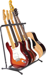 The image shows a black metal multi-guitar stand holding several guitars. It includes Stratocaster-style electric guitars, one with a sunburst finish and white pickguard, and a natural wood-colored acoustic guitar on the right. The sturdy rack is designed to organize, protect, and provide easy access to multiple instruments, commonly used by musicians, music stores, or studios.