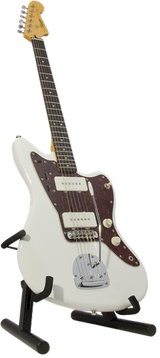 The image shows a white/cream Fender Jazzmaster-style electric guitar with a dark tortoiseshell pickguard, two single-coil pickups, a rosewood fretboard with white dot inlays, and chrome hardware. It features a traditional Fender headstock and a signature on the lower body. The guitar rests on a black adjustable A-frame stand, highlighting its classic offset design and well-maintained condition.