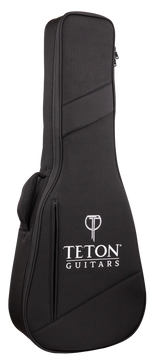 The image shows a black Teton Guitars soft gig bag made of durable fabric with padded protection. It features the white Teton logo and "T" symbol on the front, diagonal seam design, dual zippers, a top carrying handle, and a shoulder strap attachment. This lightweight, portable case is ideal for safely transporting acoustic guitars or similar-sized string instruments.