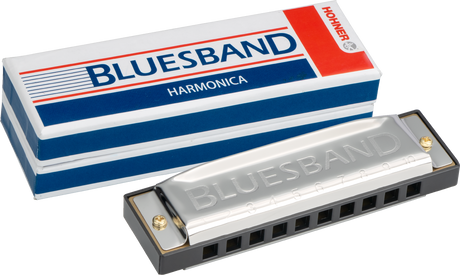 The image shows a Hohner Blues Band 10-hole diatonic harmonica with its original red, white, and blue packaging. The harmonica has a chrome-plated cover embossed with "BLUESBAND," a black plastic comb, and brass reeds inside. The packaging features Hohner branding and the model name. This reliable, entry- to intermediate-level harmonica is popular in blues, folk, and rock music.