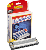 The image shows a Hohner Blues Band 10-hole diatonic harmonica in the key of C with a silver body and plastic comb, alongside its red and white Hohner Enthusiast packaging. The packaging features a player image, a "FREE ONLINE LESSONS" promotion, and the slogan "Enjoy Music - Play HOHNER!" This reliable, entry-level harmonica is popular for blues, folk, and rock music.