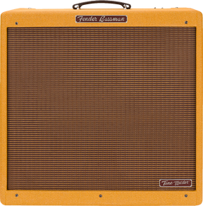The image shows a Fender Bassman Tone Master guitar amplifier with a lacquered tweed finish, brown/bronze ribbed grill cloth, and a dark brown leather handle. The rectangular combo amp features the Fender logo on the front panel and a "Tone Master" badge on the lower right. This modern digital amp recreates the classic late 1950s Bassman sound, known for its iconic vintage tone popular in blues and rock music.