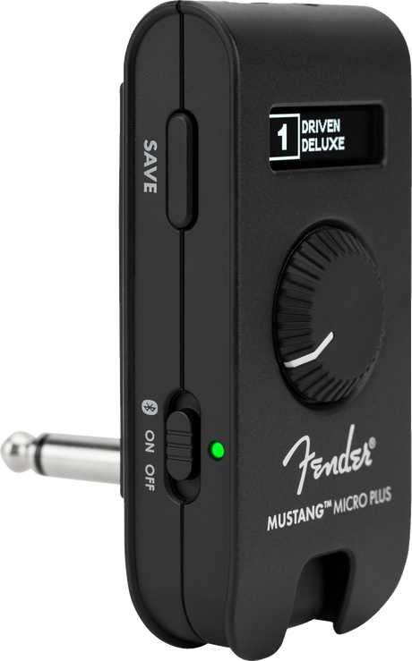 The image shows a Fender Mustang Micro Plus, a compact, portable headphone amplifier for electric guitars. It features a clip-on design, Fender branding, a display reading "1 DRIVEN DELUXE," a control knob, SAVE button, ON/OFF switch with green LED, and a 1/4" input jack. Ideal for silent practice, it offers amp simulations and effects in a small, convenient package.