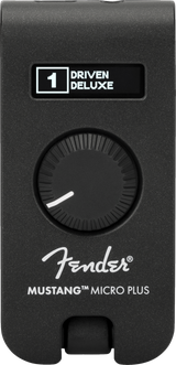 The image shows a Fender Mustang Micro Plus, a compact black guitar headphone amplifier with a textured finish. It features a digital display reading "1 DRIVEN DELUXE," a large rotary knob, the Fender logo, and the model name. The device plugs directly into an electric guitar for silent practice, offering amp simulations and effects in a portable design.