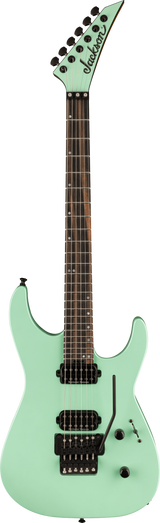 The image shows a seafoam green Jackson electric guitar with a pointed headstock and six tuning pegs. It has a dark wood fretboard with dot inlays, two black humbucker pickups, a Floyd Rose tremolo bridge, and volume and tone knobs. Featuring a superstrat body shape with cutaways, this guitar is designed for rock and metal styles, blending vintage color with aggressive modern design.