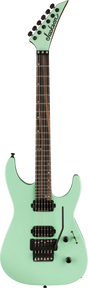 The image shows a seafoam green Jackson electric guitar with a pointed headstock and six tuning pegs. It has a dark wood fretboard with dot inlays, two black humbucker pickups, a Floyd Rose tremolo bridge, and volume and tone knobs. Featuring a superstrat body shape with cutaways, this guitar is designed for rock and metal styles, blending vintage color with aggressive modern design.
