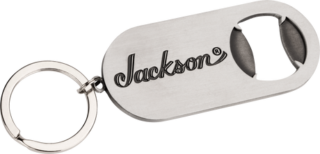 The image shows a metal keychain bottle opener branded with the Jackson logo, a well-known electric guitar manufacturer popular in rock and metal music. This promotional merchandise item highlights Jackson’s identity within the guitar industry, where they produce accessories alongside their high-performance guitars like the Soloist, Dinky, and Rhoads models.