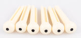 The image shows six light-colored wooden reeds, likely for woodwind instruments like clarinets or oboes, arranged in a row against a white background. Each reed is flat, thin, and rounded at one end, featuring small dark holes. The natural wood grain is visible. These reeds are essential, consumable parts for woodwind players, regularly replaced to maintain sound quality and playability.