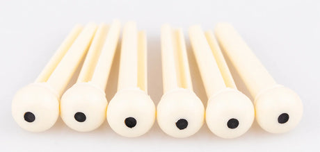 The image shows six light-colored wooden reeds, likely for woodwind instruments like clarinets or oboes, arranged in a row against a white background. Each reed is flat, thin, and rounded at one end, featuring small dark holes. The natural wood grain is visible. These reeds are essential, consumable parts for woodwind players, regularly replaced to maintain sound quality and playability.