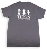 The image shows a dark gray t-shirt with "TETON GUITARS" branding. It features three white guitar headstock silhouettes—a classical guitar, an acoustic steel-string guitar, and a smaller instrument like a ukulele or mandolin—above the text. This minimalist design promotes Teton Guitars, a guitar manufacturer, and serves as branded merchandise for musicians and guitar enthusiasts.