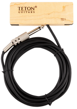 The image shows a black coiled 1/4" instrument cable from TETON Guitars with metal knurled 1/4" TS connectors on both ends. A wooden product tag with natural wood grain and TETON branding, labeled "TSC-1," accompanies the cable. This cable is designed for connecting electric guitars, basses, or other instruments to amps, pedals, or interfaces, complementing TETON’s acoustic guitar accessories.