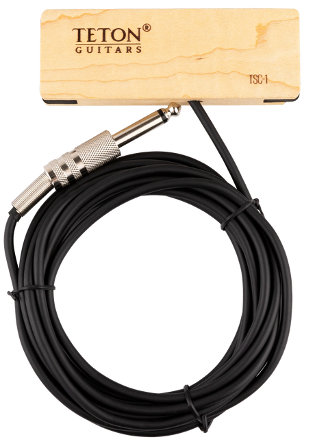 The image shows a black coiled 1/4" instrument cable from TETON Guitars with metal knurled 1/4" TS connectors on both ends. A wooden product tag with natural wood grain and TETON branding, labeled "TSC-1," accompanies the cable. This cable is designed for connecting electric guitars, basses, or other instruments to amps, pedals, or interfaces, complementing TETON’s acoustic guitar accessories.