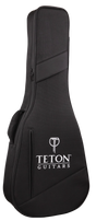 The image shows a black Teton Guitars soft guitar gig bag with a textured fabric surface, white Teton logo and brand name, and a "T" logo at the top. It features diagonal accent stripes, a full-length zipper, and padded shoulder straps. Designed for acoustic guitars, it offers lightweight, portable protection with a sleek, professional look.