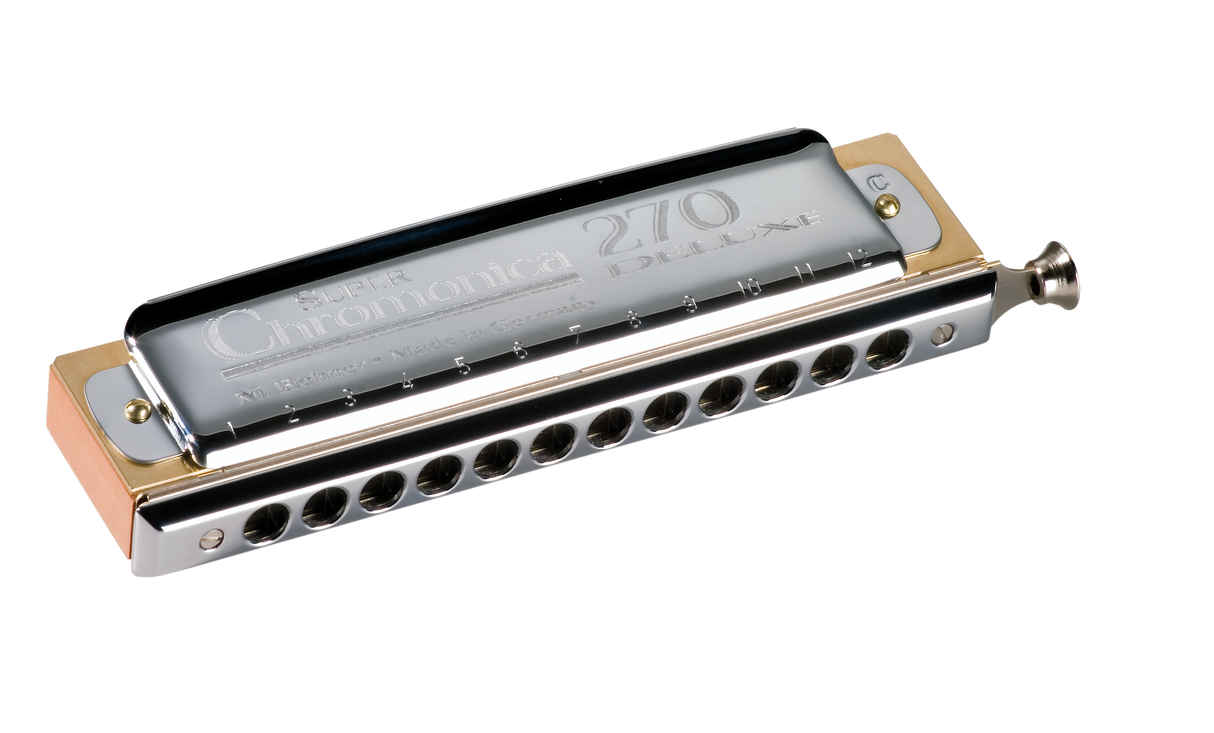 The image shows a Hohner Super Chromonica 270 Deluxe chromatic harmonica with a sleek chrome body and gold end plates. It features a rectangular shape with multiple holes and a slide button on the right side for accessing all 12 chromatic notes. This professional-grade instrument is known for its high-quality construction and is favored by jazz, classical, and blues musicians for its versatility and premium finish.