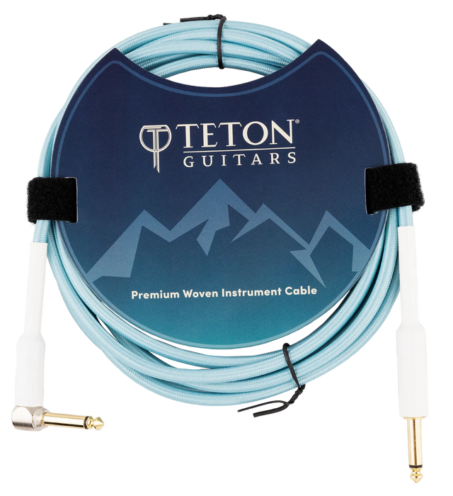 The image shows a Teton Guitars Premium Woven Instrument Cable with a light blue woven exterior for durability. It features gold-plated 1/4" TS connectors—one straight and one right-angle—and includes Velcro ties for organization. The cable is neatly coiled and displayed in professional packaging with Teton Guitars branding, designed for connecting electric guitars or basses to amplifiers or audio gear.