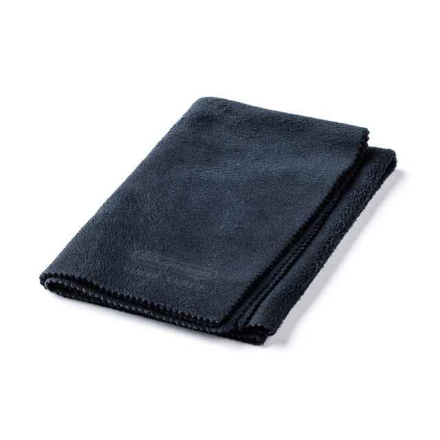 The image shows a dark-colored microfiber cleaning cloth with finished edges, designed for musical instrument care. Ideal for polishing guitars, violins, brass instruments, and more, it removes fingerprints, dust, and moisture without scratching. This lint-free cloth helps maintain the instrument’s finish and appearance, making it an essential accessory for musicians to keep their instruments clean and in good playing condition.