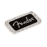The image shows a Fender logo badge, a decorative metal emblem featuring the iconic silver "Fender" script on a black background. It is bordered by small metallic studs or rivets. Typically used on guitar amplifiers, cases, or Fender gear, this high-quality badge highlights brand loyalty and adds a stylish, detailed finishing touch to musical equipment.