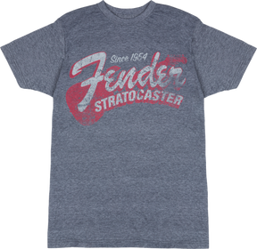 The image shows a heather gray Fender t-shirt featuring vintage-style graphics celebrating the iconic Fender Stratocaster guitar. The design includes "Since 1954," large "Fender" script, bold "STRATOCASTER" text, and a stylized guitar silhouette. This music merchandise appeals to fans and musicians, honoring one of the most influential electric guitars in history.