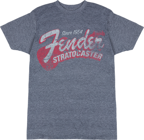 The image shows a heather gray Fender t-shirt featuring vintage-style graphics celebrating the iconic Fender Stratocaster guitar. The design includes "Since 1954," large "Fender" script, bold "STRATOCASTER" text, and a stylized guitar silhouette. This music merchandise appeals to fans and musicians, honoring one of the most influential electric guitars in history.