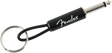 The image shows a Fender-branded keychain designed to look like a guitar cable. It features a 1/4" guitar plug on one end, a metal keyring on the other, and a black cable-like connector with the white Fender logo. This music-themed accessory mimics an instrument cable and is a novelty item for guitar players and Fender fans to carry keys while showing brand loyalty.