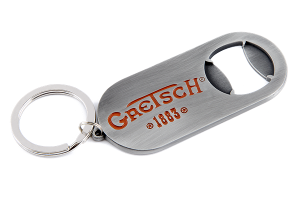 The image shows a Gretsch branded bottle opener keychain with the orange/red Gretsch logo and "1883" marking. It has a brushed metal finish, a built-in bottle opener, and an attached keyring. This promotional item represents the musical instrument company known for guitars and drums, especially hollow-body electric guitars used by artists like Chet Atkins and George Harrison.