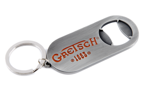 The image shows a Gretsch branded bottle opener keychain with the orange/red Gretsch logo and "1883" marking. It has a brushed metal finish, a built-in bottle opener, and an attached keyring. This promotional item represents the musical instrument company known for guitars and drums, especially hollow-body electric guitars used by artists like Chet Atkins and George Harrison.