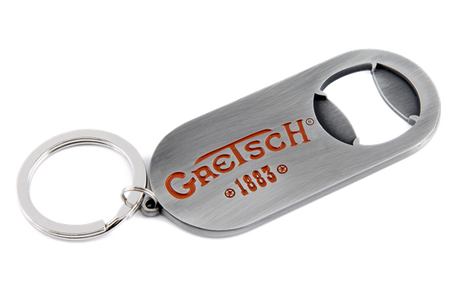 The image shows a Gretsch branded bottle opener keychain with the orange/red Gretsch logo and "1883" marking. It has a brushed metal finish, a built-in bottle opener, and an attached keyring. This promotional item represents the musical instrument company known for guitars and drums, especially hollow-body electric guitars used by artists like Chet Atkins and George Harrison.