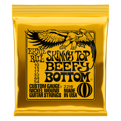 Ernie Ball Skinny Top Beefy Bottom guitar strings gold packaging on a white background