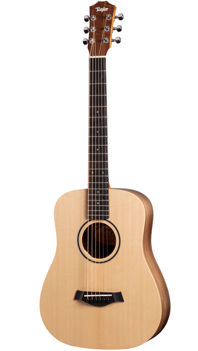 The image shows a Taylor small-bodied acoustic guitar, likely from the Academy or entry-level series. It features a natural spruce top, darker wood back and sides, and a dark rosewood or ebony fretboard. Chrome tuning pegs (3+3), a black bridge, and a round soundhole with a dark rosette are visible. The guitar has a clean, simple design, suitable for beginners to intermediate players and various acoustic styles.