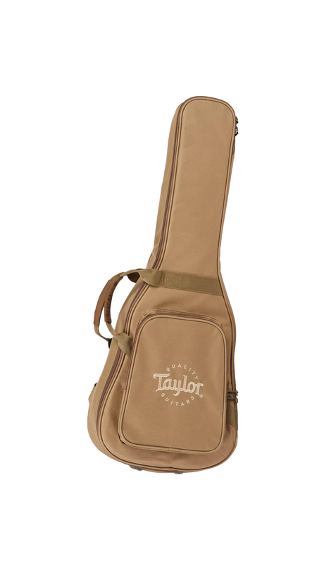 The image shows a tan Taylor guitar gig bag with the Taylor Guitars logo and "QUALITY GUITARS" text on the front pocket. This padded soft case features dual handles, shoulder straps, multiple compartments, and a full-length zipper. Made of durable material, it is designed to protect and transport acoustic guitars. Taylor is a well-known American guitar maker, and this lighter, portable gig bag is an accessory for their acoustic guitars.