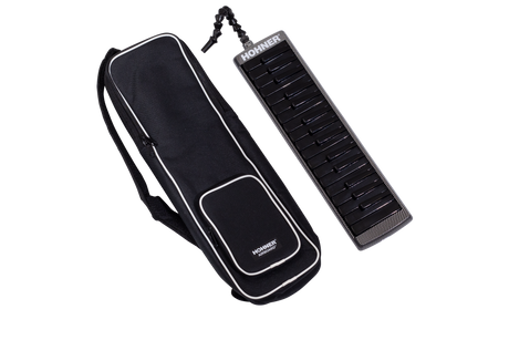 The image shows a black Hohner melodica with white and black piano-style keys alongside its black carrying case with white trim. The case has shoulder straps and a front pocket for easy transport. A flexible tube mouthpiece is attached to the melodica. This wind instrument produces sound by blowing air through the mouthpiece while pressing keys and is popular in music education and various genres for its portable, unique sound.