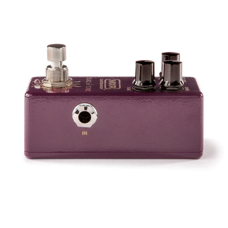 The image shows a compact, purple/burgundy guitar effects pedal with a metal enclosure. It features one silver footswitch on the left, two black control knobs on the top right, and an input jack labeled "IN" on the front. The pedal has standard 1/4" audio jacks for guitar and amp connections, with some text on the top surface. This stompbox-style pedal is used by musicians to alter guitar sound effects during performances.