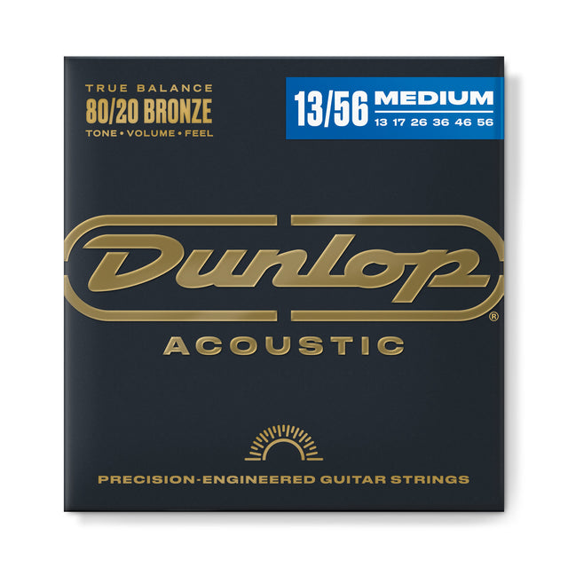 The image shows a package of Dunlop Acoustic Guitar Strings, 80/20 Bronze with a medium gauge of 13-56. The set includes strings sized 13, 17, 26, 36, 46, and 56. These precision-engineered strings offer a balanced tone, volume, and feel. The packaging features Dunlop’s gold logo on a dark background with blue labeling for the gauge. 80/20 bronze is known for bright tone and strong projection.