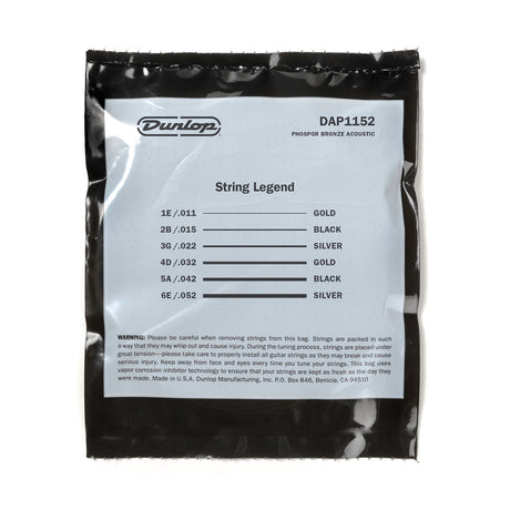 The image shows a package of Dunlop DAP1152 "String Legend" phosphor bronze acoustic guitar strings. It contains a complete light gauge (11-52) set with six strings: 1E/.011 (gold), 2B/.015 (black), 3G/.022 (silver), 4D/.032 (gold), 5A/.042 (black), and 6E/.052 (silver). The vacuum-sealed pack preserves freshness and includes safety warnings.